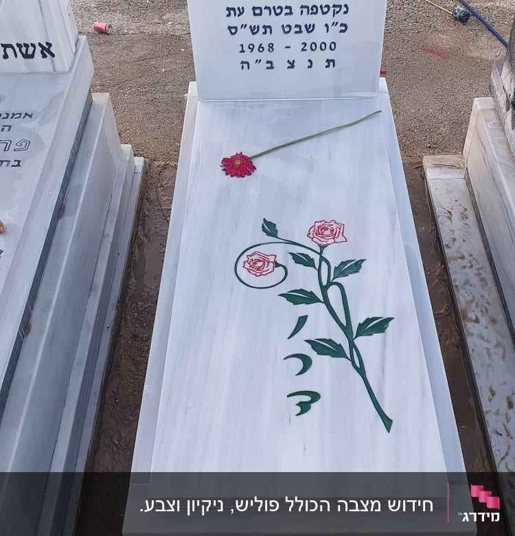 מצבה לבנה עם כיתוב בעברית ופרח אדום